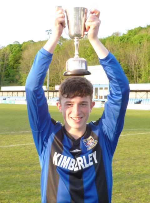 Jake Merry holds the cup aloft for Hakin United U16s